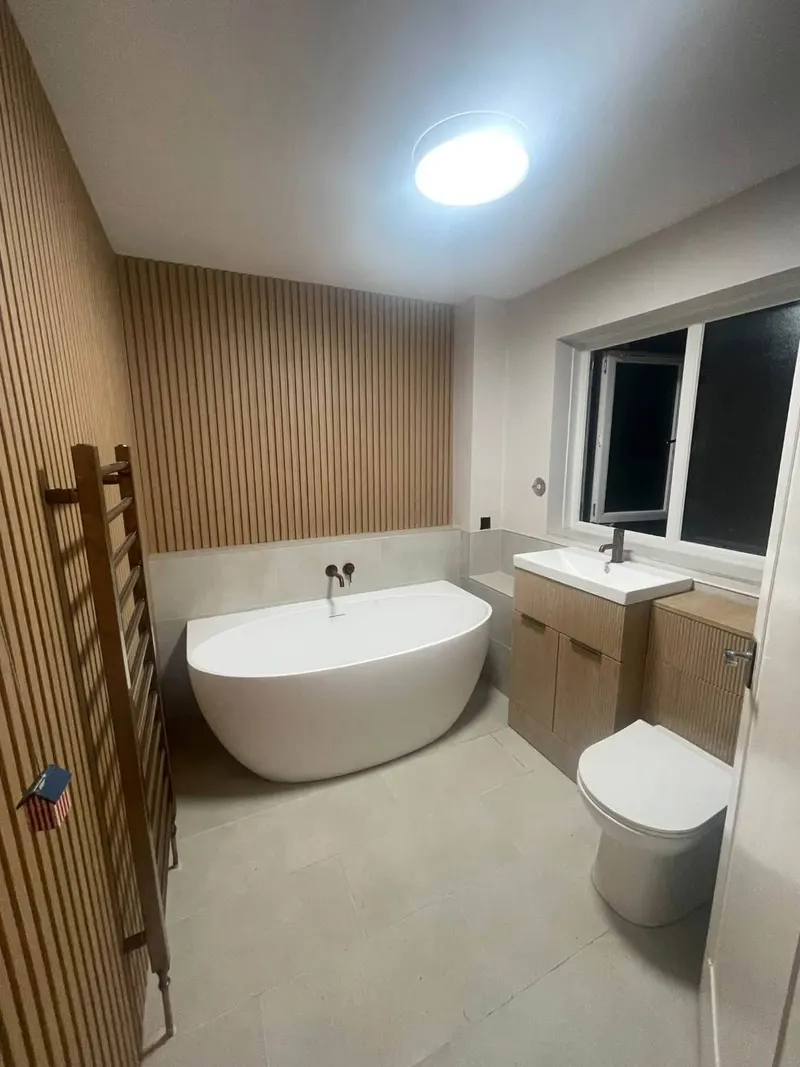Finished bathroom by OJP Plumbing with freestanding bath, wall-mounted bronze taps, fluted vanity unit and ladder towel rail